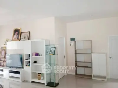 Spacious living room with modern white furniture and sleek glass display cabinet.