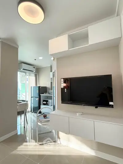 Modern living room with sleek TV setup and open kitchen layout in bright apartment
