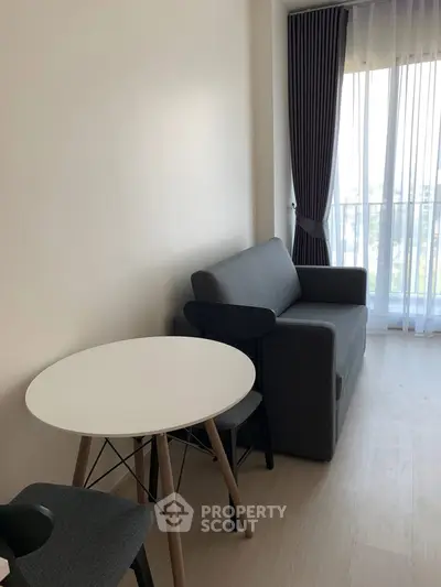 Modern living room with sleek furniture and natural light from large window.