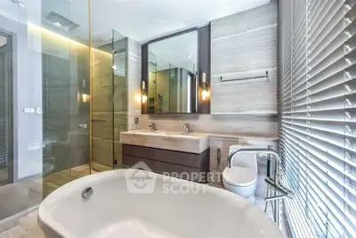 Luxurious modern bathroom with freestanding bathtub and glass shower enclosure.