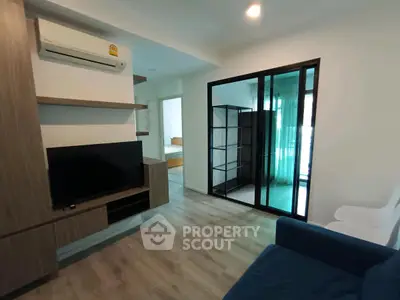 Modern living room with sleek design and air conditioning, featuring a cozy blue sofa and wooden flooring.