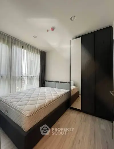 Modern bedroom with large window and sleek wardrobe in a stylish apartment.