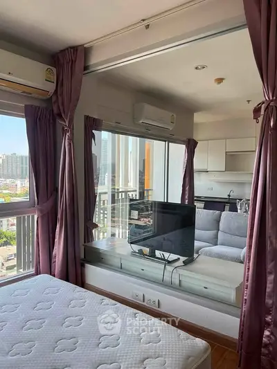 Modern apartment with city view, featuring cozy living room and bedroom separated by glass partition.