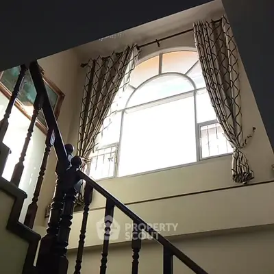 Elegant staircase with large window and stylish curtains