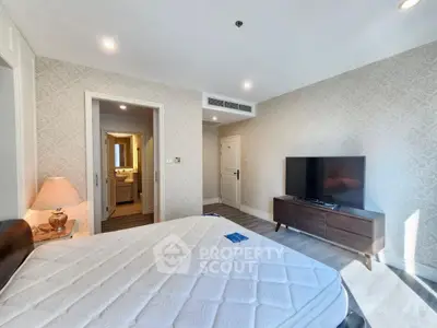 Spacious bedroom with modern decor and ensuite bathroom in luxury apartment.