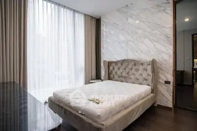 Luxurious bedroom with plush bed and marble accent wall in modern apartment