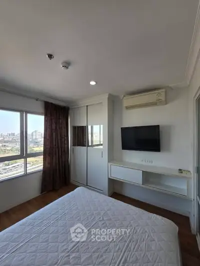 Modern bedroom with city view, featuring a wall-mounted TV and air conditioning.