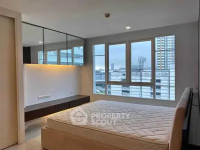 Spacious bedroom with large windows offering city views in modern apartment