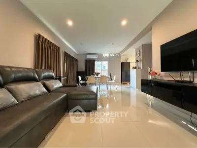 Spacious modern living room with sleek leather sofa and dining area, perfect for entertaining.