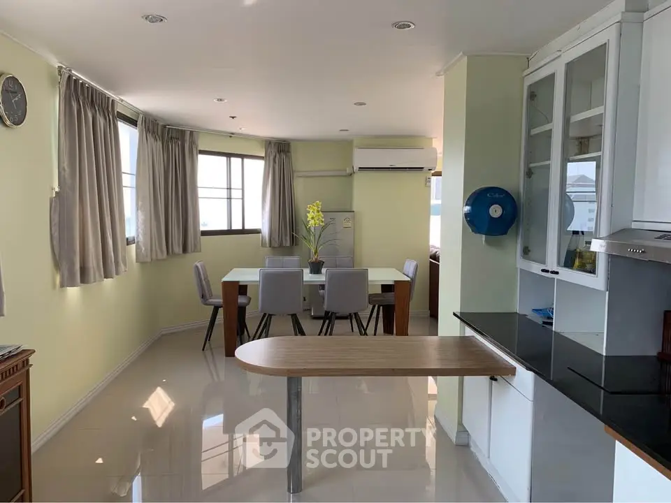 Spacious dining area with modern kitchen and large windows for natural light.