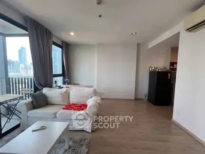 Spacious living room with modern decor and city view balcony in high-rise apartment.
