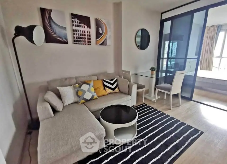Modern living room with stylish decor and open layout, featuring a cozy sofa and chic glass partition.