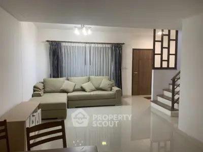 Spacious living room with modern sofa and elegant staircase in a cozy home setting.