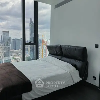 Modern bedroom with city skyline view, featuring sleek black leather headboard and large windows.