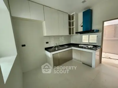 Modern kitchen with sleek cabinetry and black countertops in a new apartment.