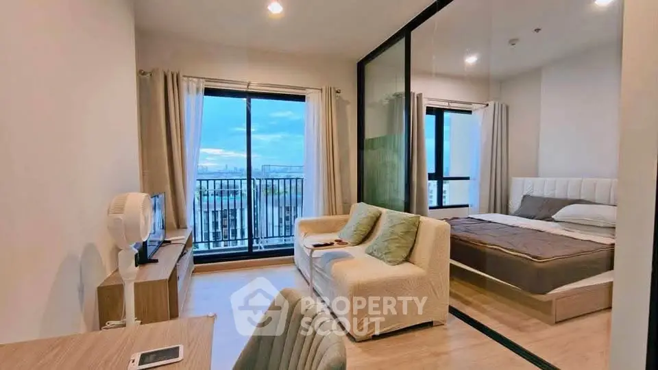 Modern studio apartment with glass partition, cozy living area, and stunning city view from balcony.
