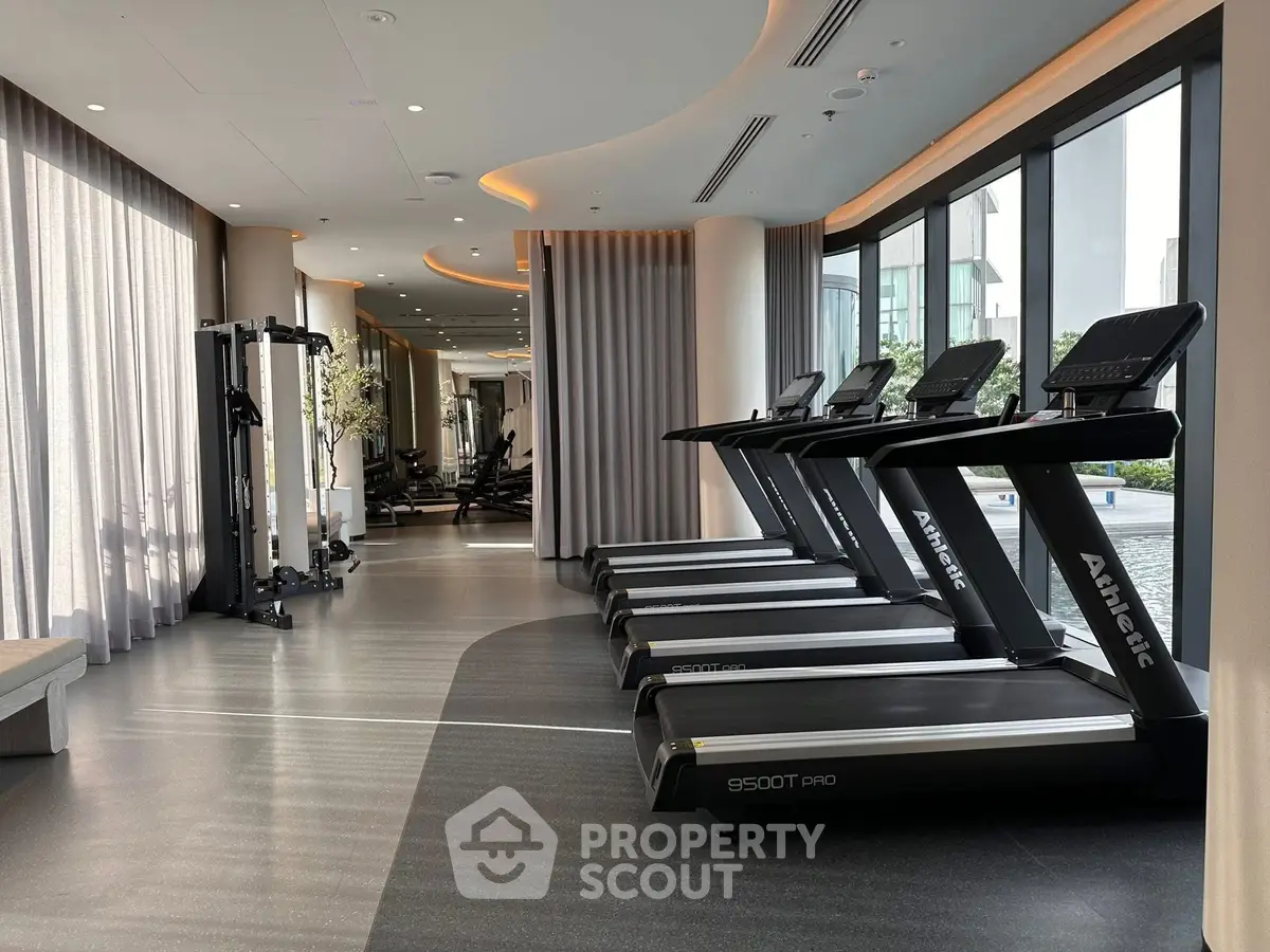 Luxurious gym with modern equipment and large windows in upscale residential building.