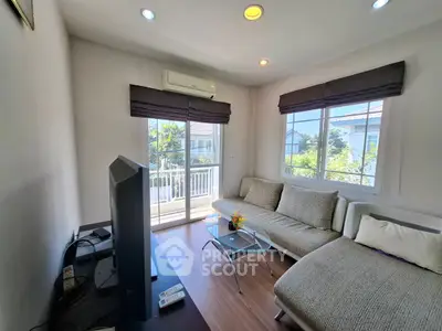 Bright living room with modern sofa and large windows overlooking balcony.