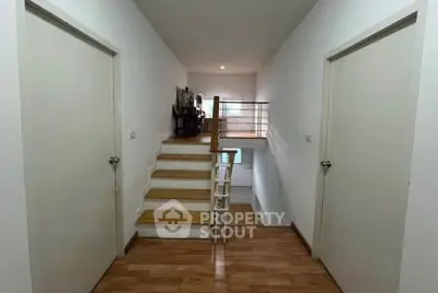 Modern interior hallway with wooden flooring and staircase leading to upper level.