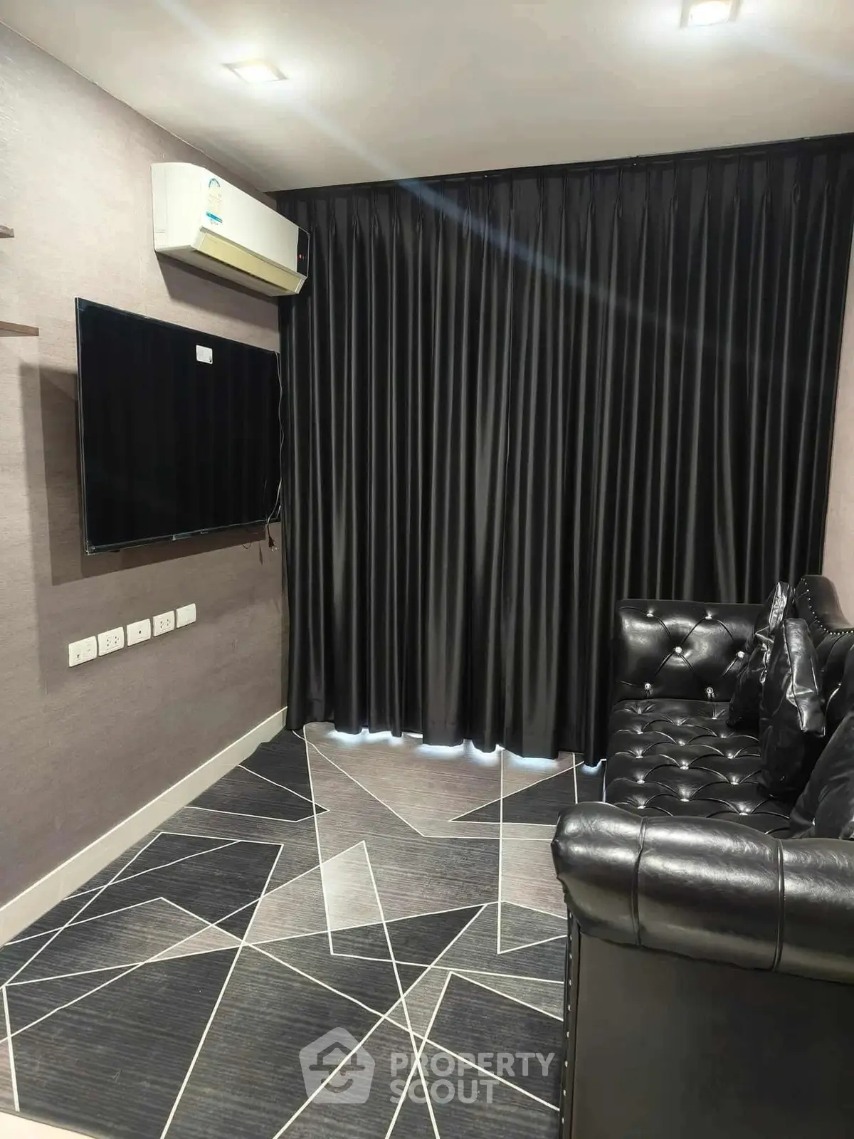 Modern living room with sleek black leather sofa and geometric patterned floor