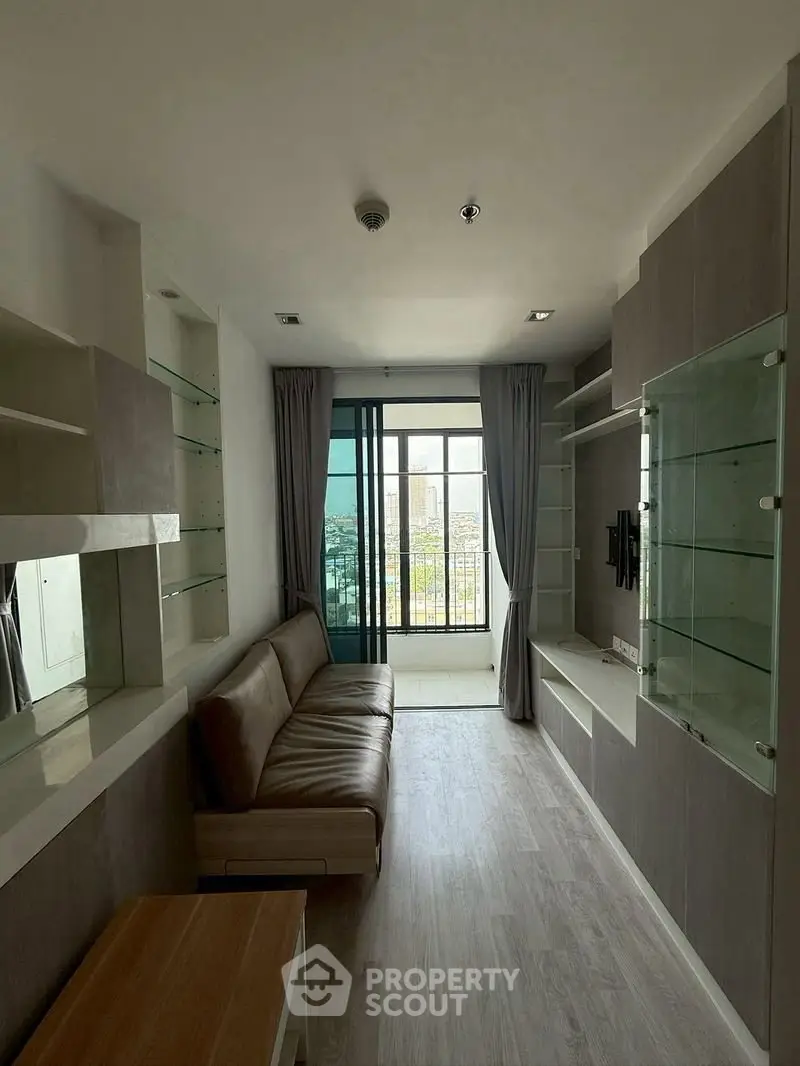 Modern living room with sleek design and city view from large window, featuring stylish shelving and comfortable seating.