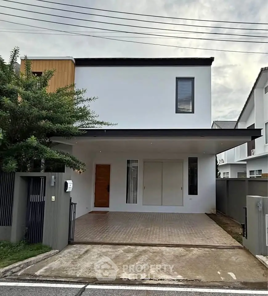 Modern two-story house with minimalist design and spacious driveway in a suburban neighborhood.