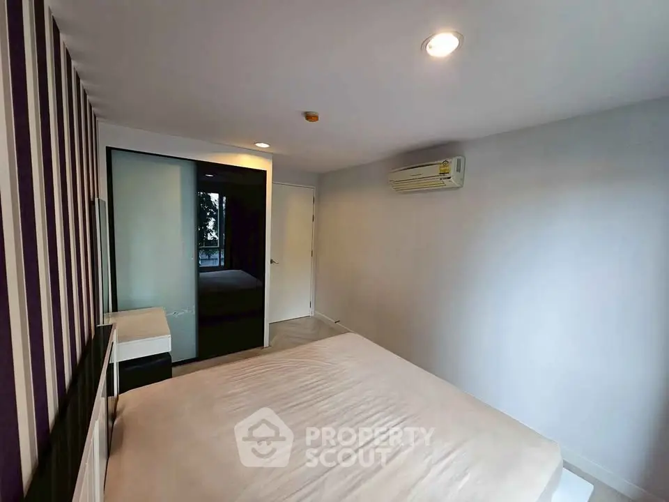 Modern bedroom with stylish striped accent wall and sleek air conditioning unit.