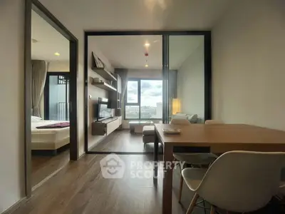 Modern apartment interior with open living room and bedroom, featuring large windows and stylish furniture.