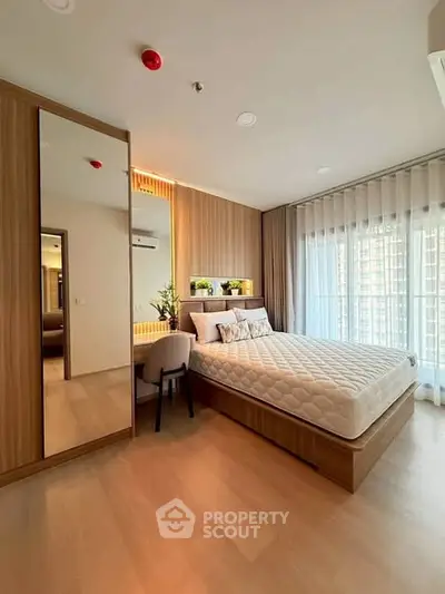 Modern bedroom with large window, wooden flooring, and stylish decor in a high-rise apartment.