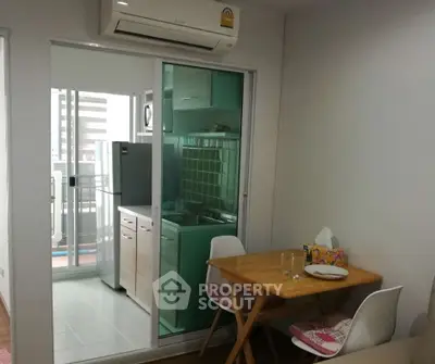 Cozy dining area with compact kitchen and balcony view in modern apartment.