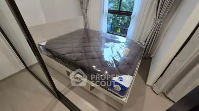 Modern bedroom with large window and new mattress in sleek interior design.