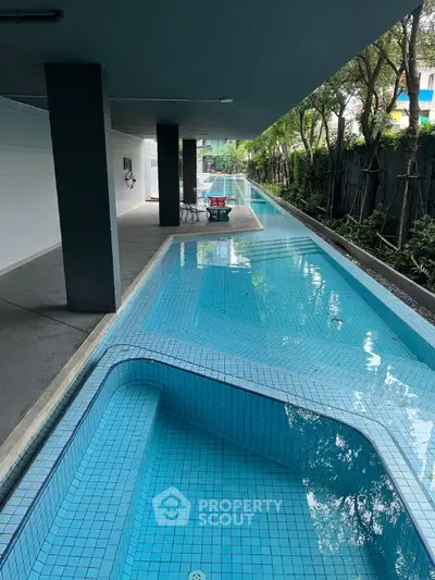 Luxurious modern swimming pool with sleek design and lush greenery in upscale residential complex.