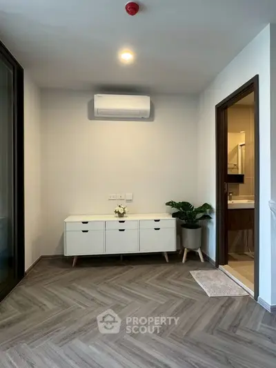 Modern living space with stylish flooring and air conditioning, adjacent to a sleek bathroom.