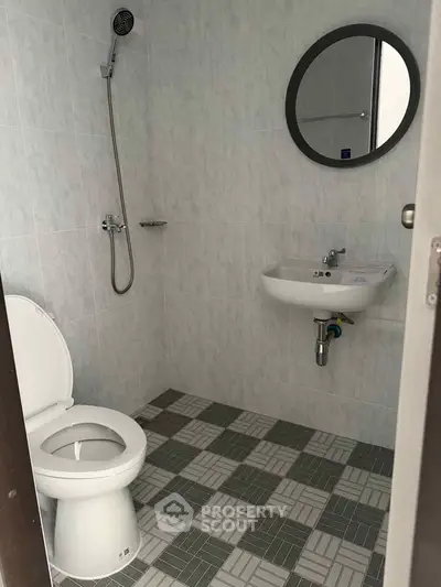 Compact bathroom with shower, toilet, and sink in a tiled setting.