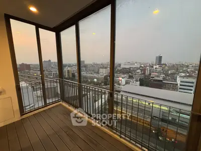 Stunning city view from a modern high-rise balcony with glass walls and wooden flooring.