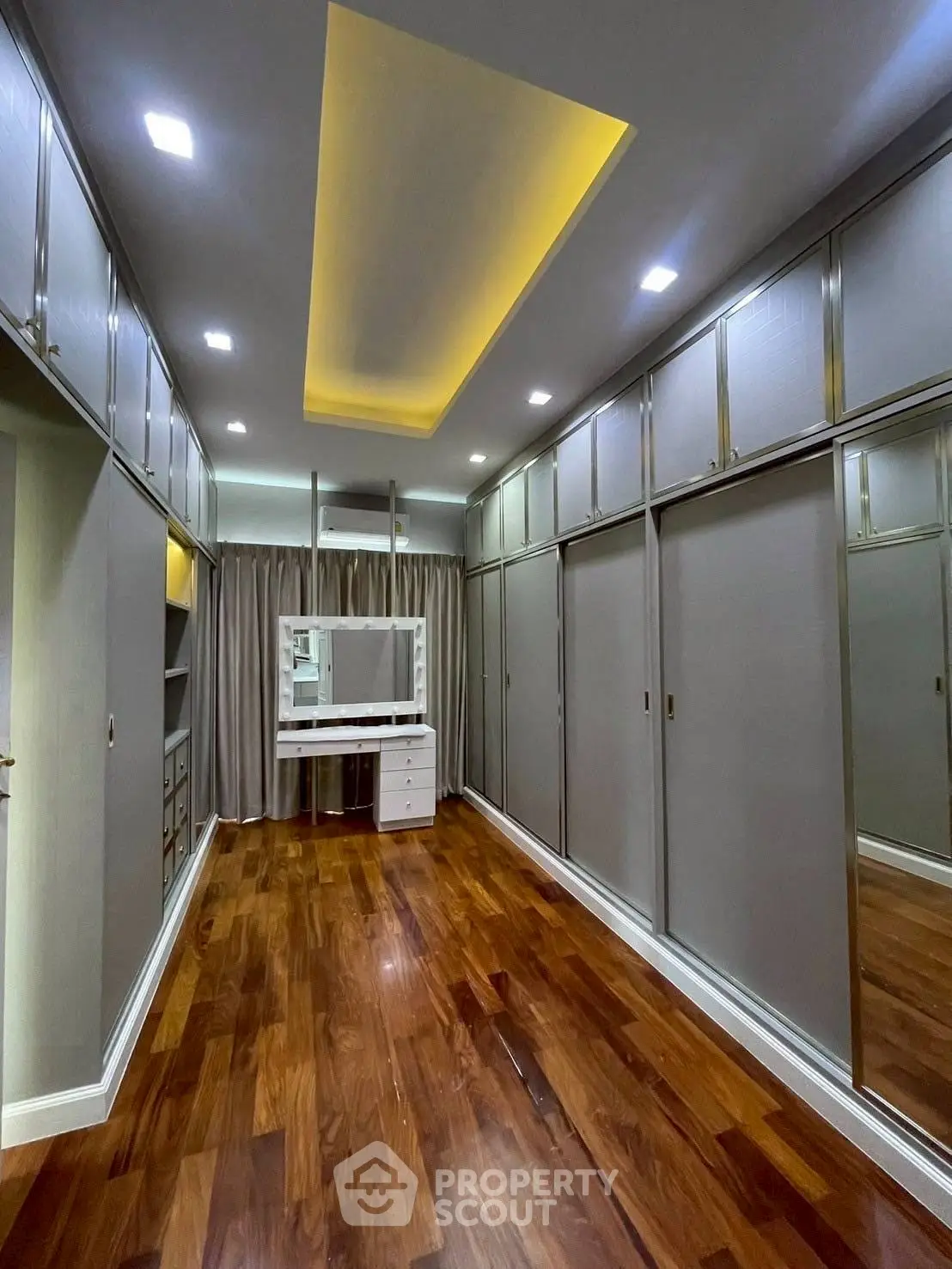 Luxurious walk-in closet with elegant wood flooring and ample storage space.