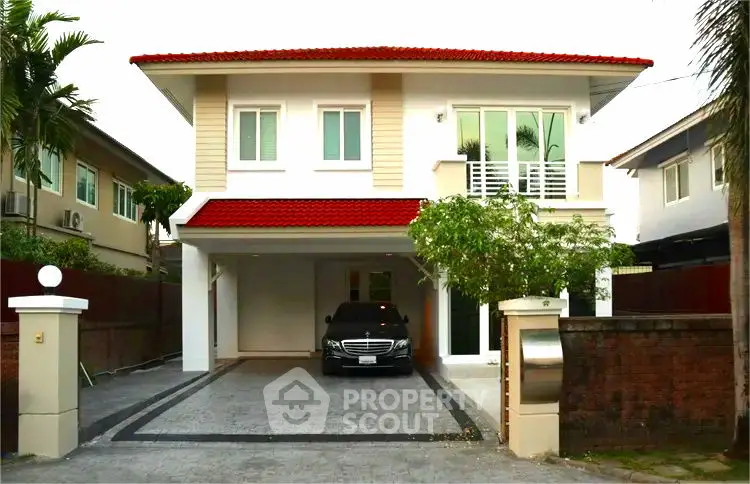 Charming two-story house with red roof and spacious driveway in a serene neighborhood.