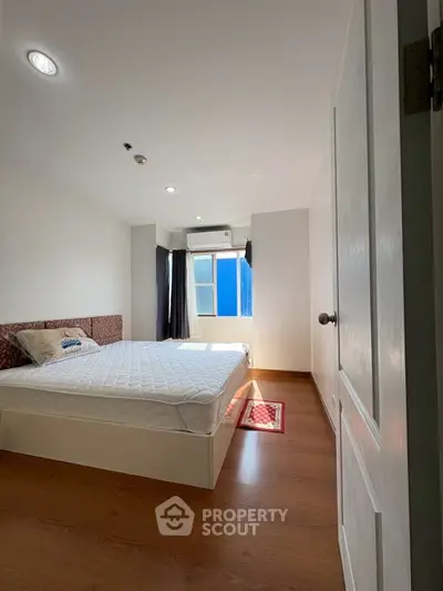Bright and airy bedroom with wooden flooring and large window for natural light.