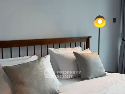 Cozy bedroom with elegant wooden bed and stylish floor lamp, perfect for relaxation.