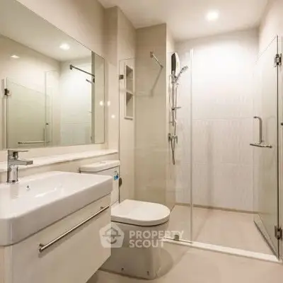 Modern bathroom with glass shower enclosure and sleek fixtures.
