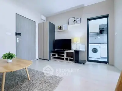 Modern living room with stylish decor and view into a compact kitchen with washing machine.