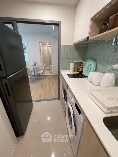 Modern kitchen with sleek appliances and open layout leading to dining area.