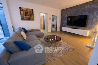 Spacious modern living room with large sofa and wall-mounted TV, perfect for relaxation.