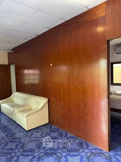 Spacious living area with wooden paneling and vintage blue patterned flooring.