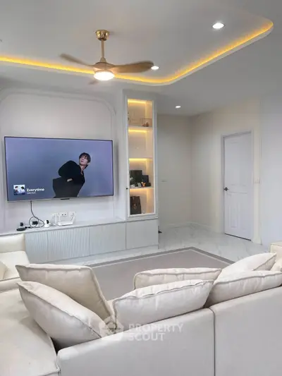 Modern living room with sleek design, built-in shelves, and large TV for entertainment.