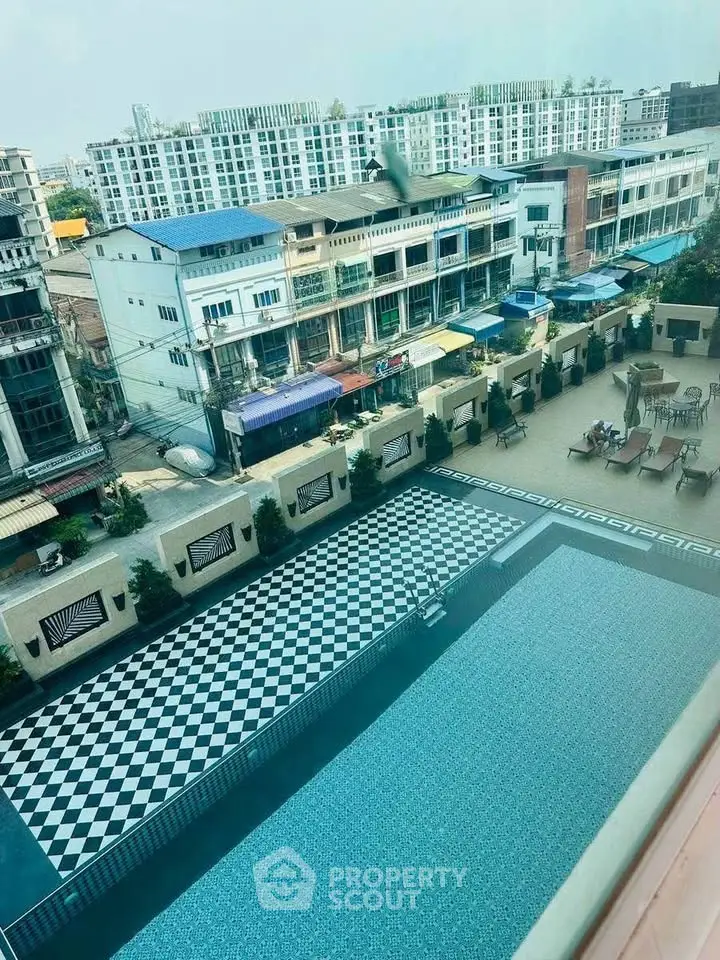 Stunning aerial view of a modern residential complex with a stylish pool and cityscape backdrop.