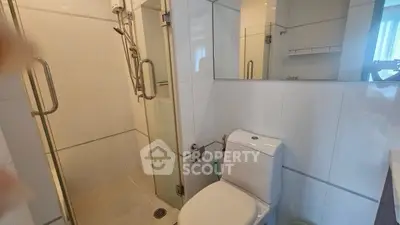 Modern bathroom with glass shower and sleek white tiles, perfect for contemporary living.