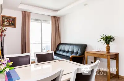 Bright and inviting living space with sleek white dining table, comfortable black leather sofa, and warm wooden accents complemented by natural light from the balcony door.