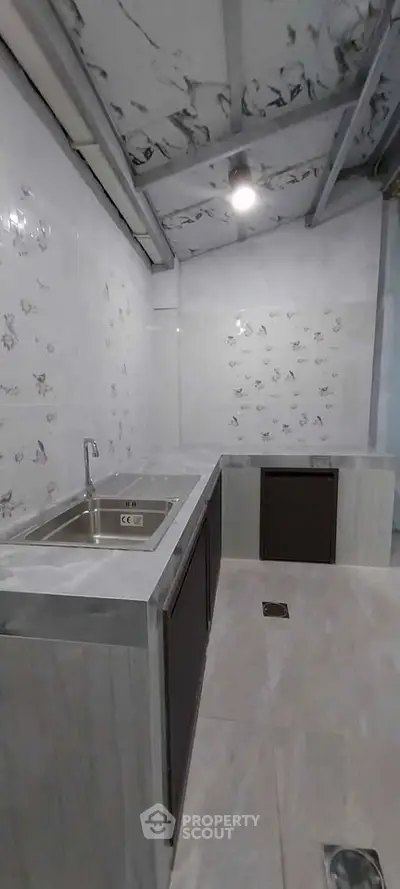 Modern kitchen with sleek countertops and stainless steel sink in a minimalist design.
