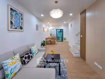 Modern living room with stylish decor and open dining area, featuring elegant lighting and contemporary furniture.